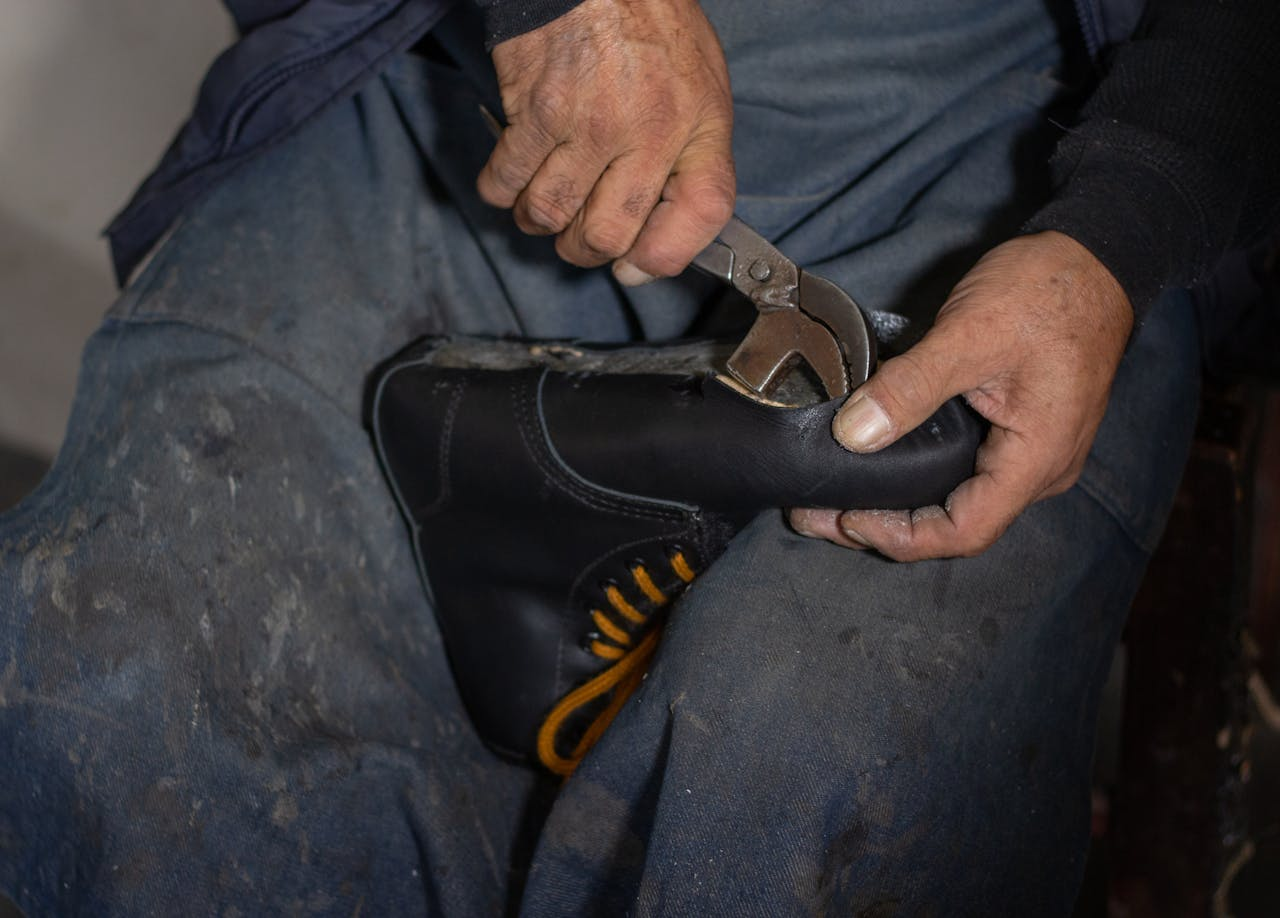 A skilled craftsman uses a tool to repair a leather shoe, showcasing traditional shoemaking techniques.