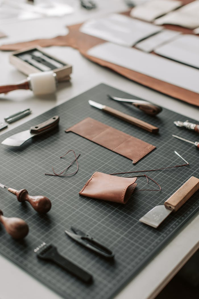 Close-up of tools and materials on a leather crafting workspace, showcasing artisanal craftsmanship.