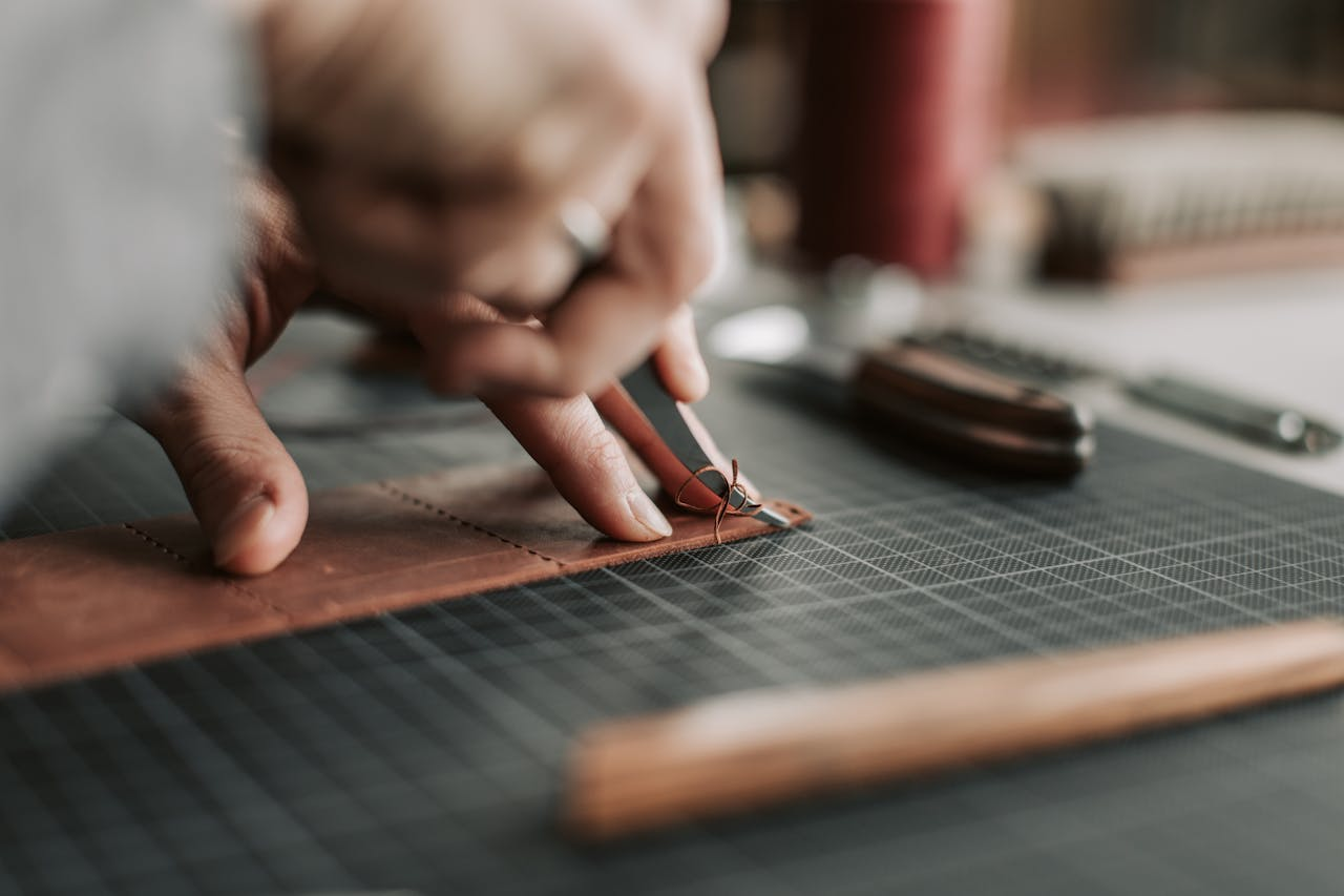 Close-up of hands intricately working on a leather piece in a crafting workshop.