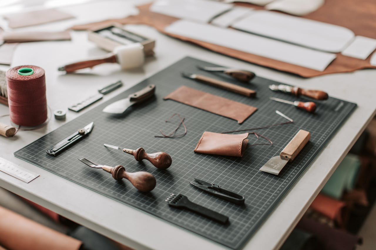 Close-up of leatherworking tools on a cutting mat in a workshop setting, showcasing craftsmanship.