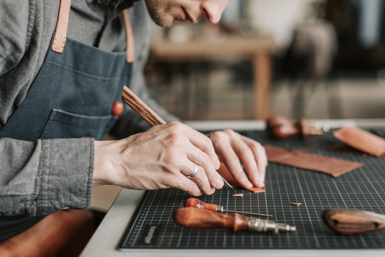 Close-up of an artisan skillfully crafting leather goods by hand in a workshop environment.